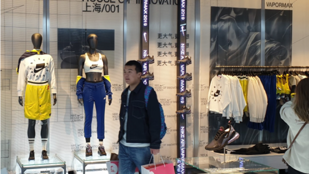 client sortant de la boutique Nike House of Innovation à Shanghai avec un sac d'achats